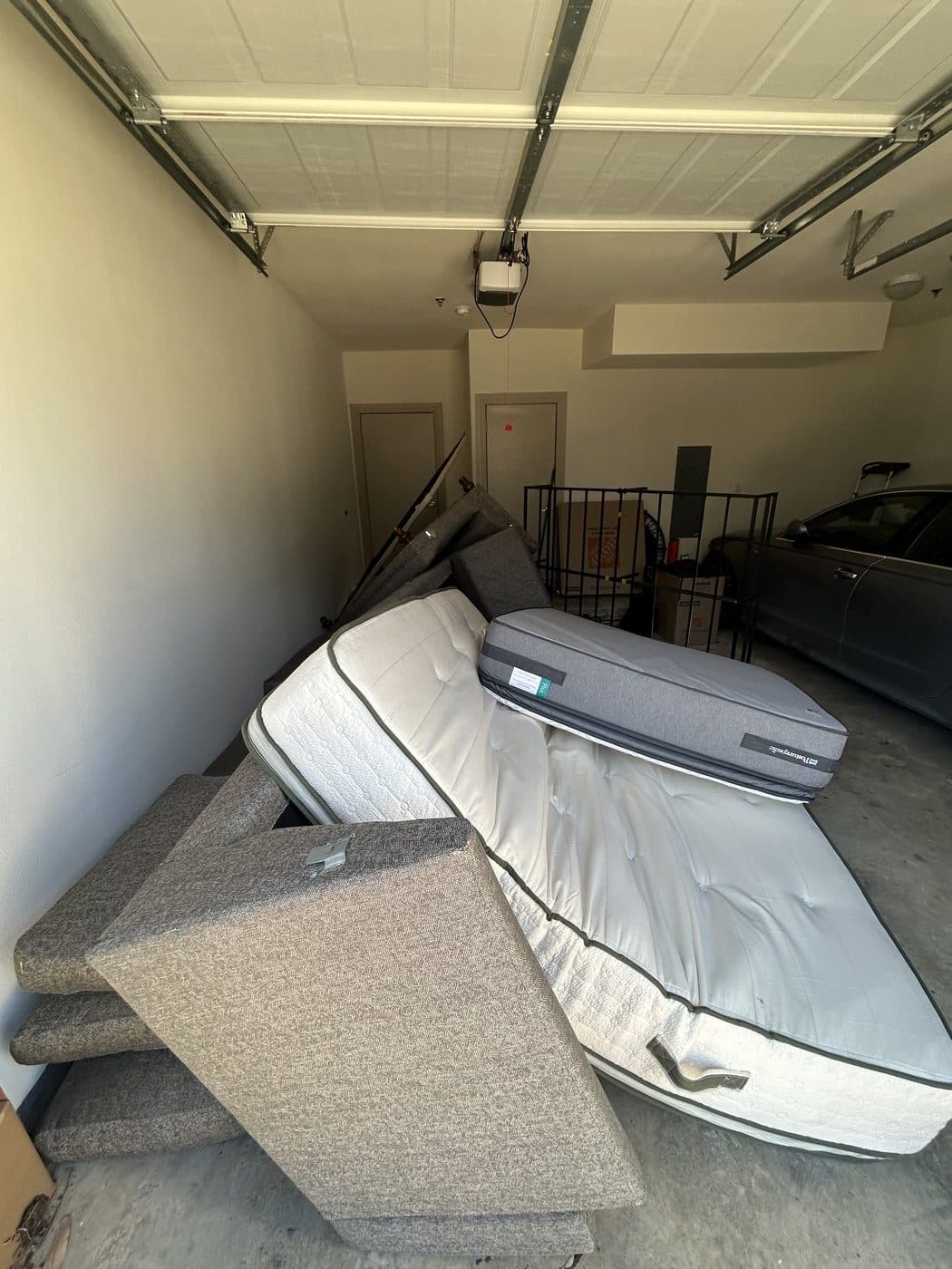 Garage blocked by old mattresses and a sectional couch before removal